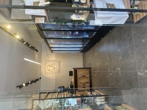 פנים החנות — דלפק העץ, מקררי הזכוכית לאורך הקיר ותאורה חמה